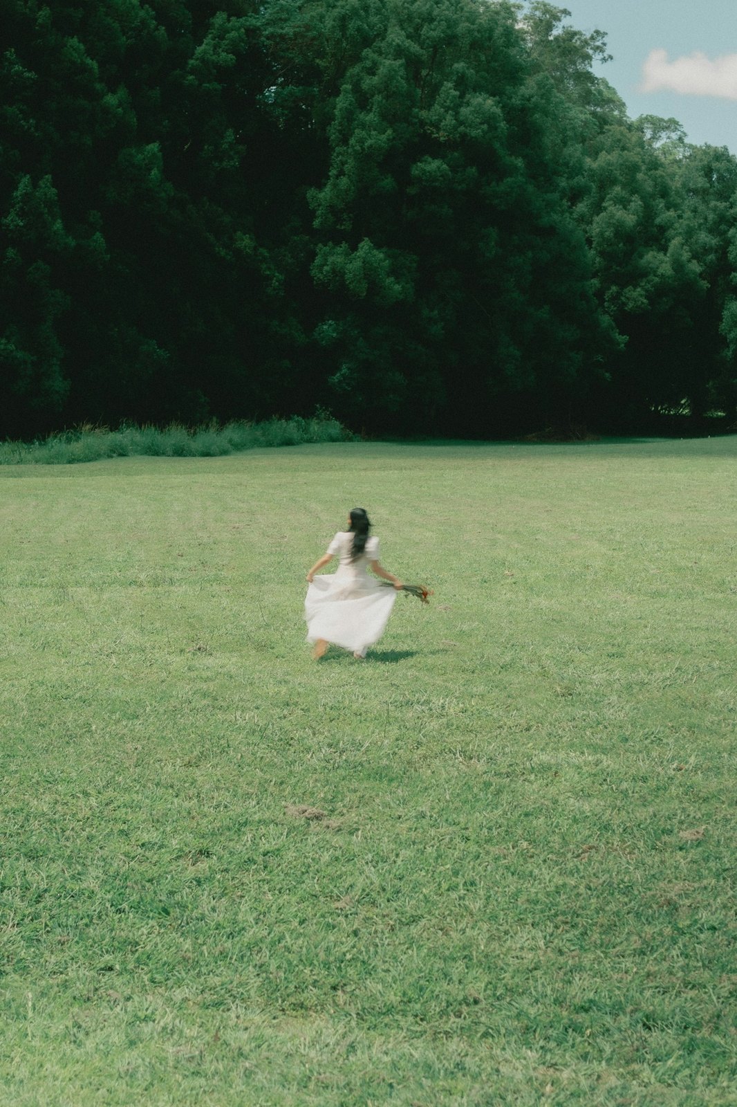 A figure in white moving through an open green field