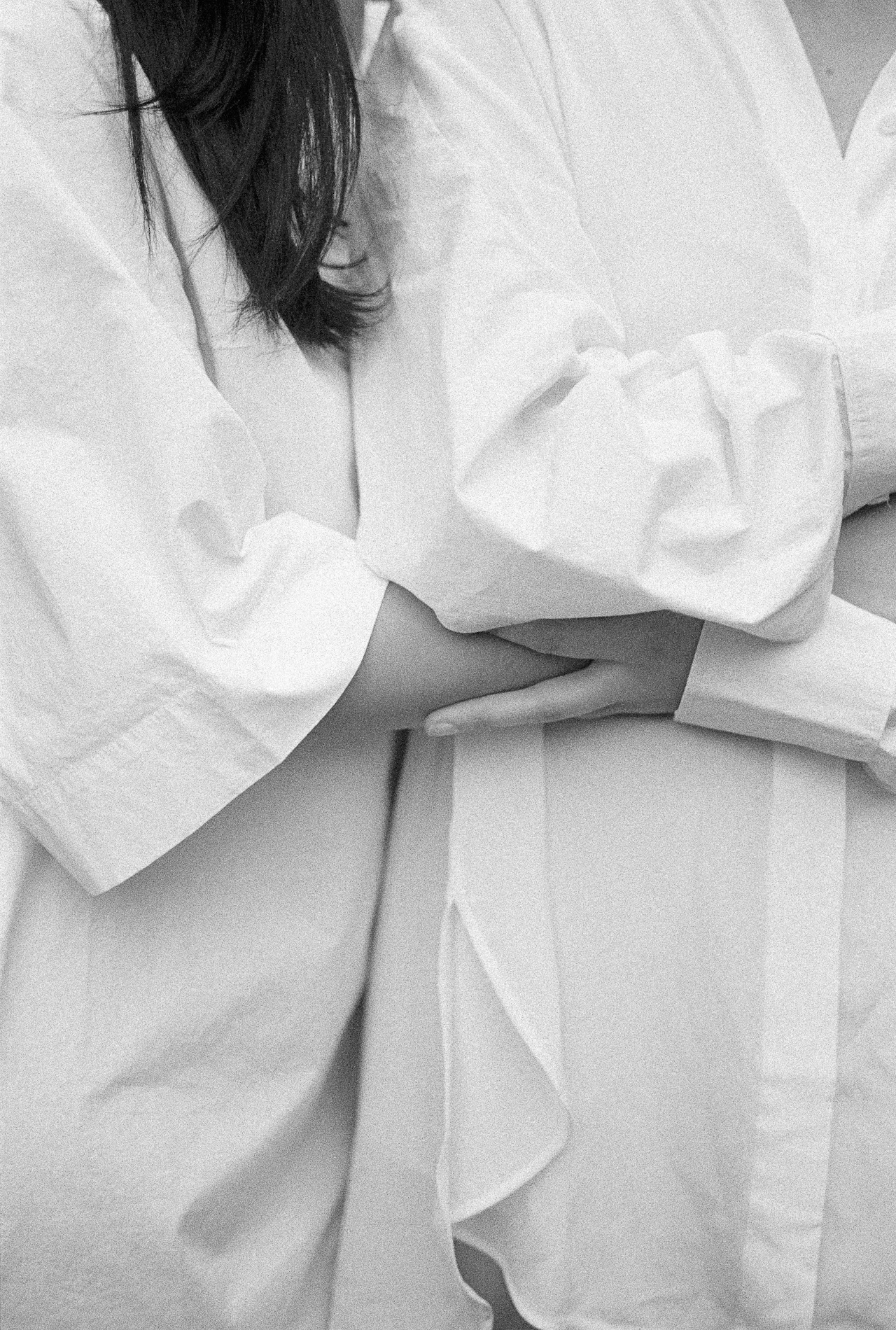 Two people in white, arms linked in a quiet gesture of closeness